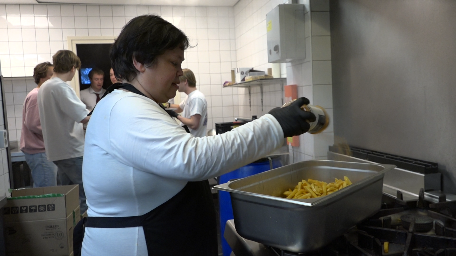 Chef Karin seasoning the fries for the main course. She is in the kitchen of student association Laurentius